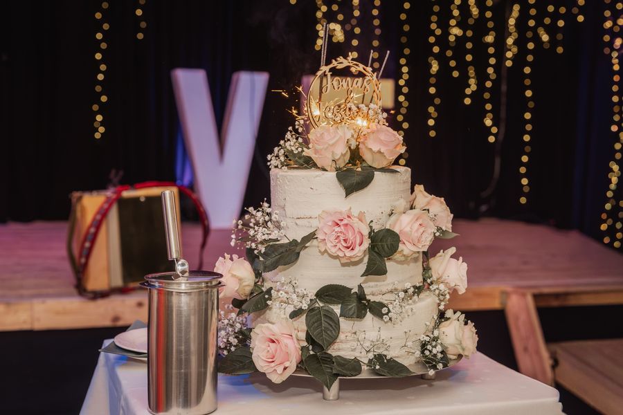 Die dreistöckige Hochzeitstorte mit rosa Rosen, Schleierkraut und Wunderkerzen