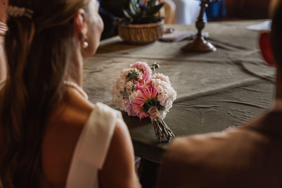 Der Brautstrauß mit rosa Dahlien und weißen Hortensien liegt während der Trauung auf dem Tisch