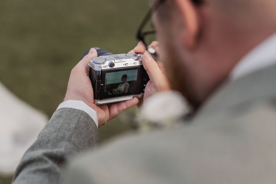 Dominik fotografiert Christina mit seiner Fuji-Kamera, auf dem Display ist sie lachend zu sehen