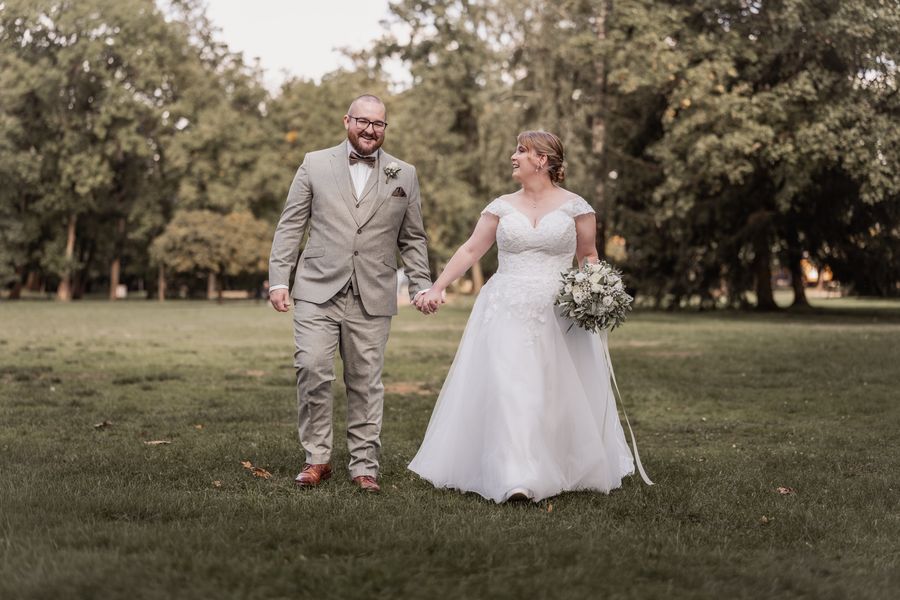 Christina und Dominik laufen lachend Hand in Hand durch einen Park
